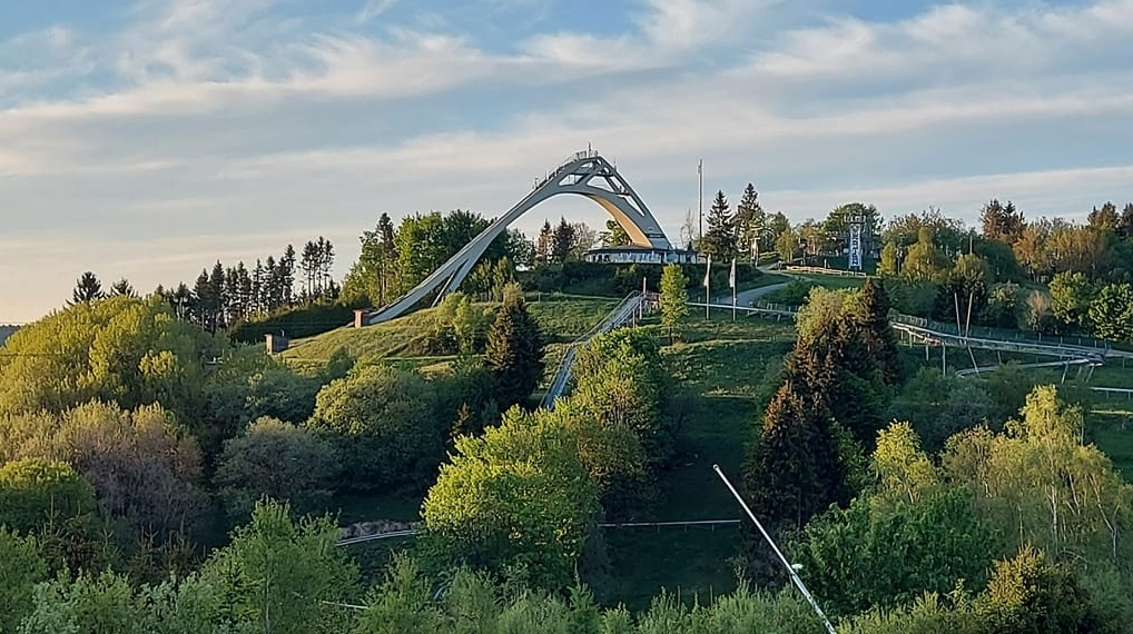 A Picturesque Ski Slope With A Bridge Gracefully Spanning Over It, Offering A Scenic View Of The Snowy Landscape.