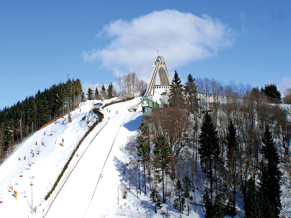 Scenic Ski Slope With A Lift And A Charming Church In The Background.